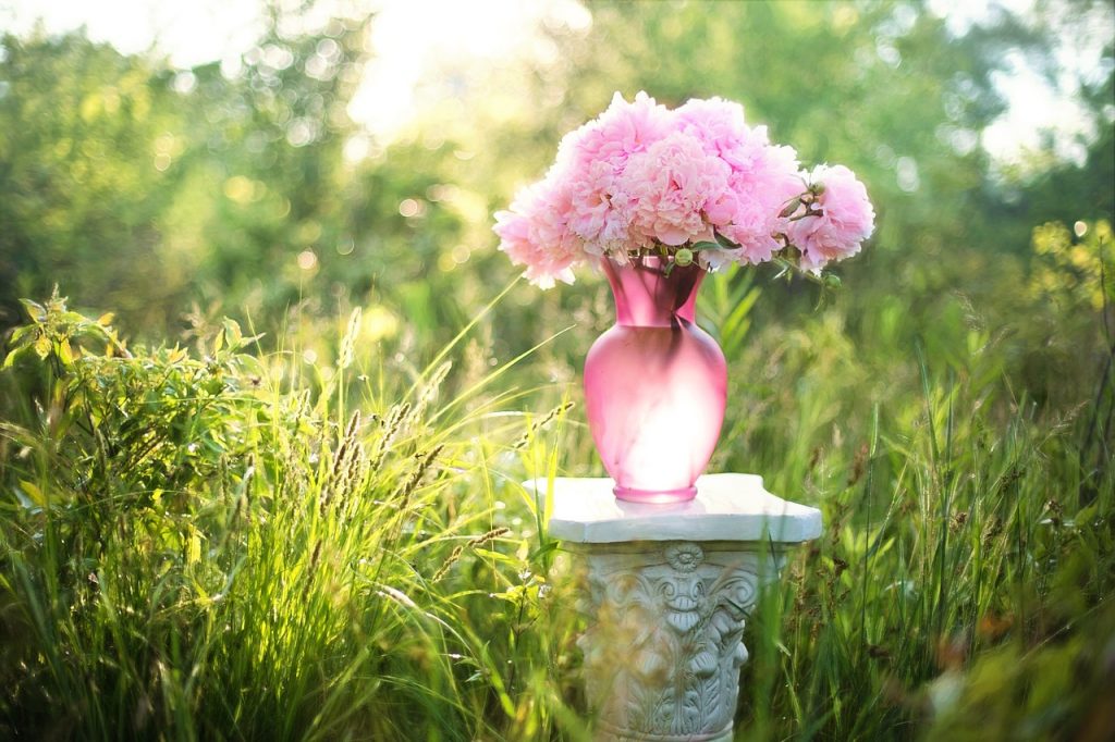 Jarrón rosa con un ramo de flores sobre una mesa en el jardín